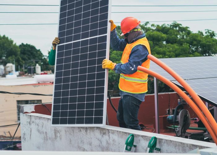 A technician in safety gear installs a solar panel on a rooftop, promoting renewable energy.